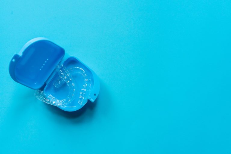 Invisalign clear aligners in a protective case on a blue background