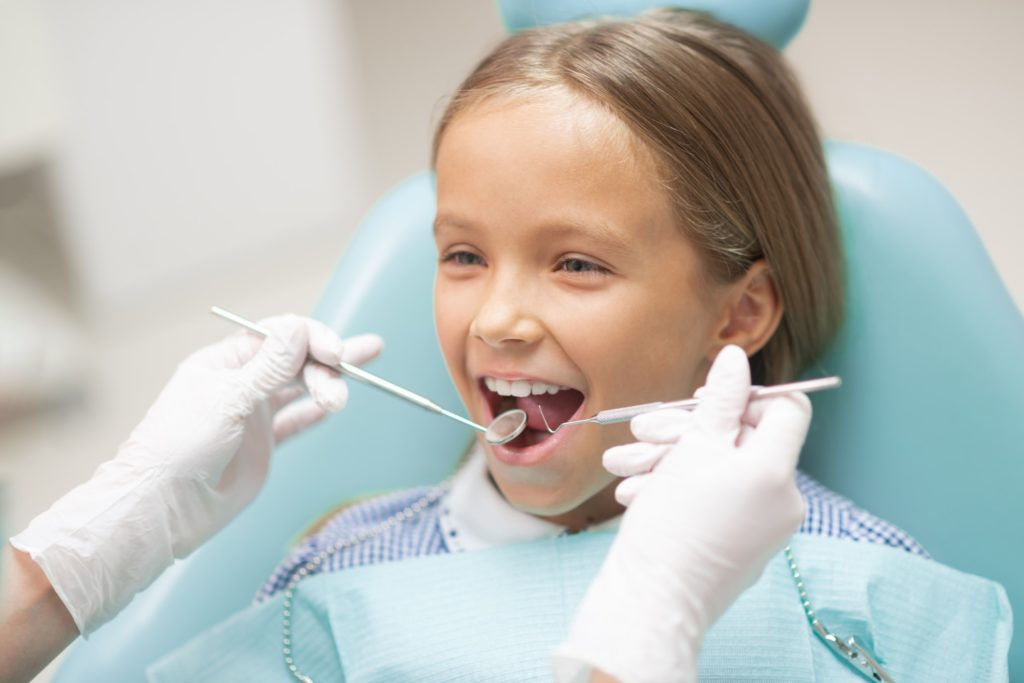 A young girl sitting in a dental chair getting a dental checkup