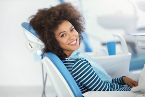 Female dental patient sits in an exam chair and looks over her shoulder smiling