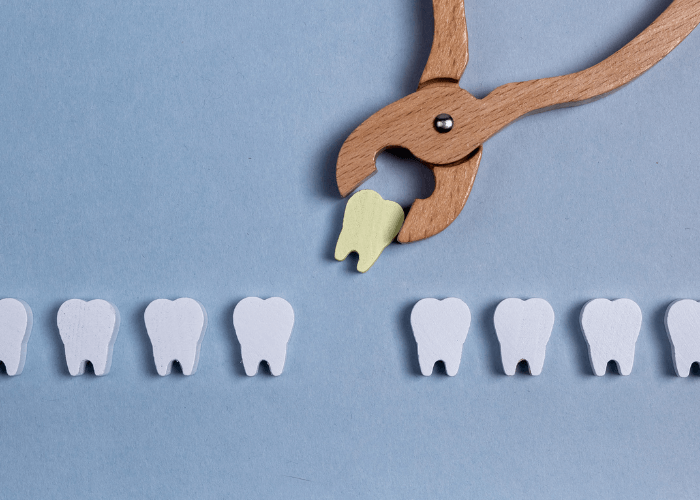 A wooden dental tool extracting a tooth from a row of white wooden teeth on a blue background.